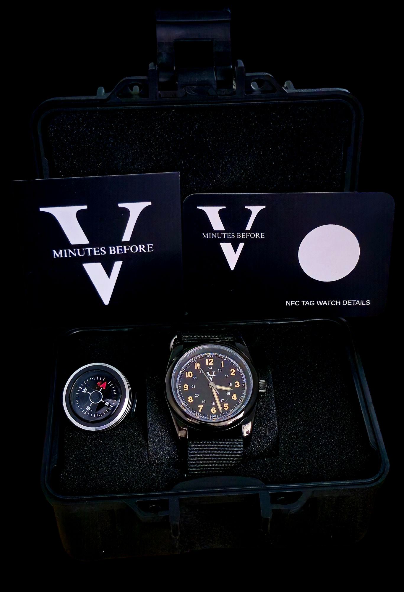 The ECLIPSE (Field Watch 36mm) by Five Minutes Before has a black face, white numerals, and a black strap. Displayed in a sleek black case next to two cards and a compass-like device, its stainless steel elements shine. The phrase MINUTES BEFORE V is elegantly visible on the cards.