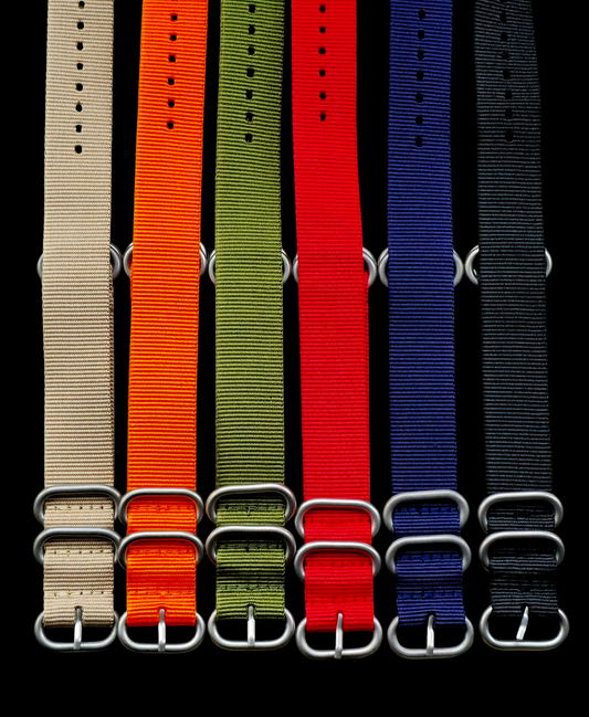 A military-style watch alongside a camera, both displaying on a vibrant red strap, emphasising their rugged design..